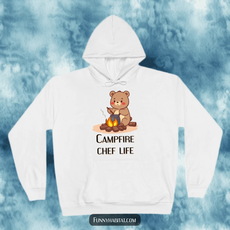 Funny bear character happily stirring a pot over a small campfire, a warm and humorous hoodie for camping trips.